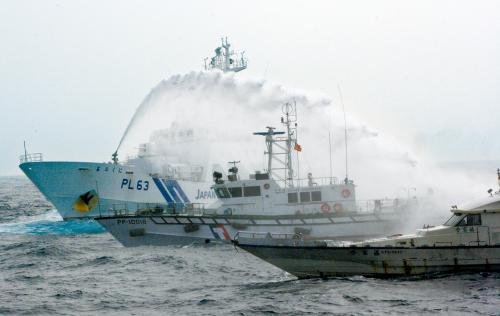 臺(tái)灣“海巡署”的巡邏船（中）在掩護(hù)保釣船“全家?！碧?hào)（右）躲避日本海上保安廳巡視船的水炮攻擊。